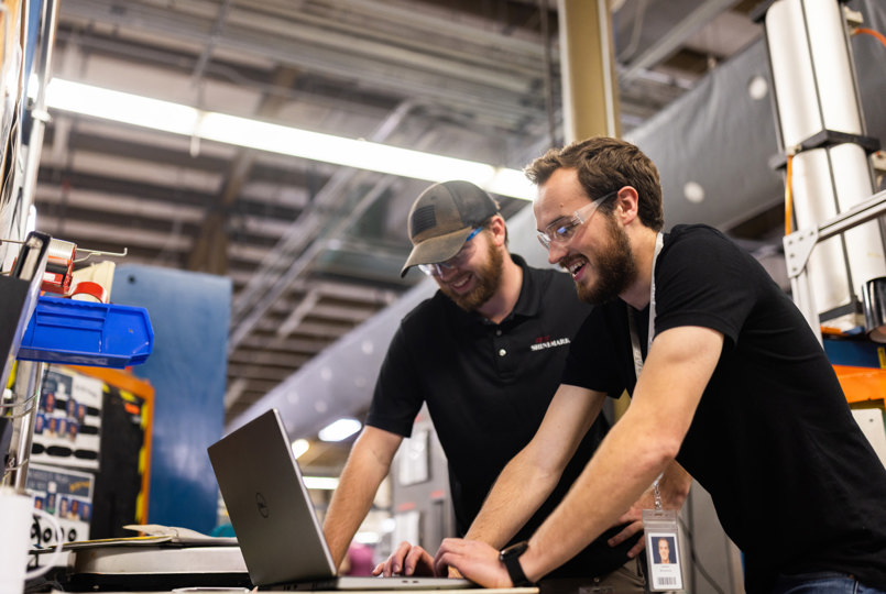 Two employees gathered around a laptop