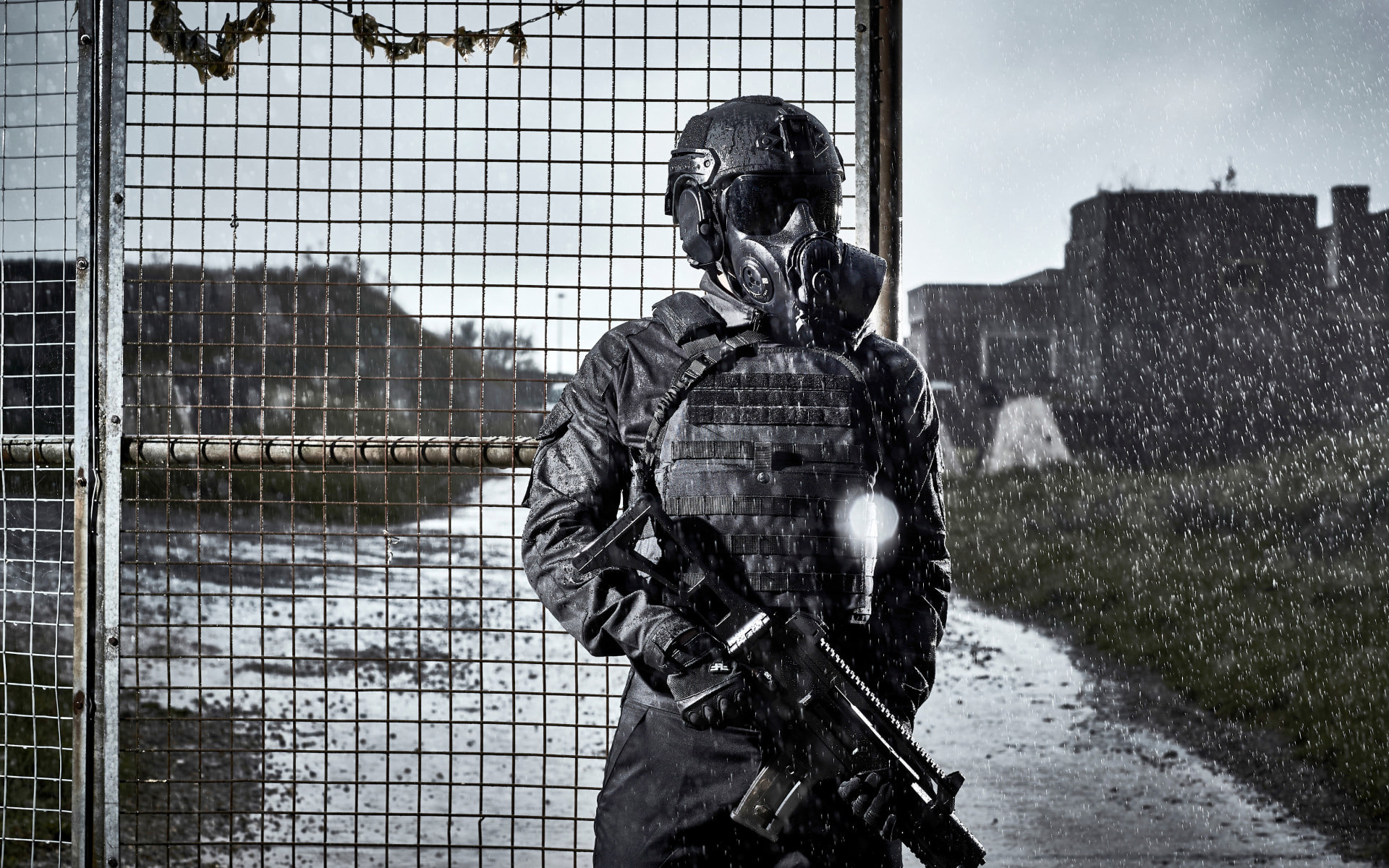 Soldier wearing a helmet and respirator guarding a fence