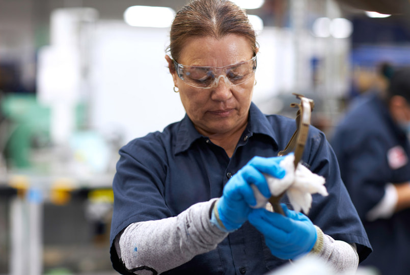 Employee quality checking a helmet part