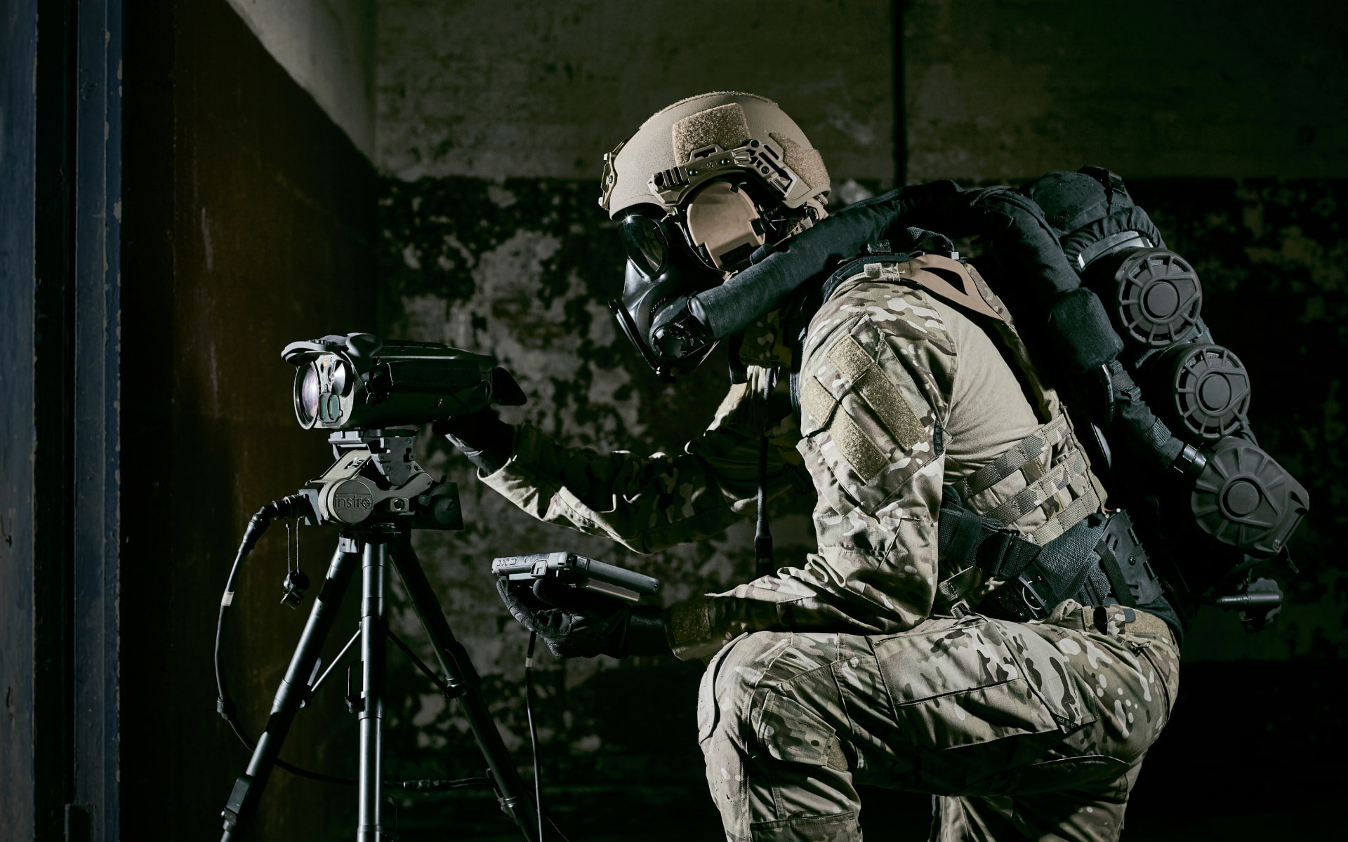 Soldier looking through a tripod wearing a helmet and respiratory protection system